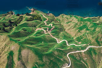 Aerial view of winding coastal road through green hills