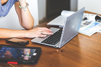 Woman typing on laptop with tablet and smartphone on desk