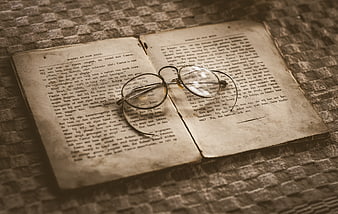Vintage open book with reading glasses on textured fabric