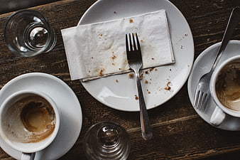 Overhead view of empty coffee cups and dirty plate on wooden table
