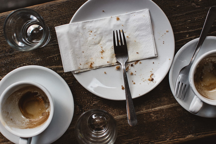 Overhead view of empty coffee cups and dirty plate on wooden table
