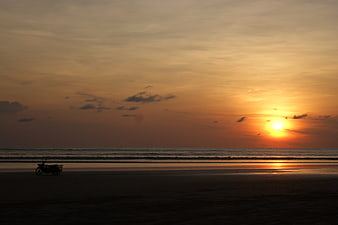 Silhouette of Motorcycle on Beach at Golden Sunset