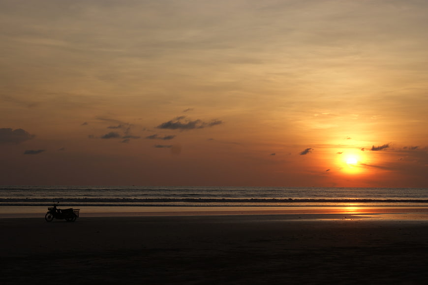 Silhouette of Motorcycle on Beach at Golden Sunset