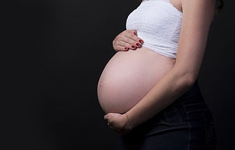 Pregnant woman holding belly in white top