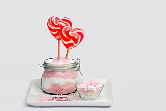 Heart-shaped lollipops in a jar with pink sugar and marshmallows
