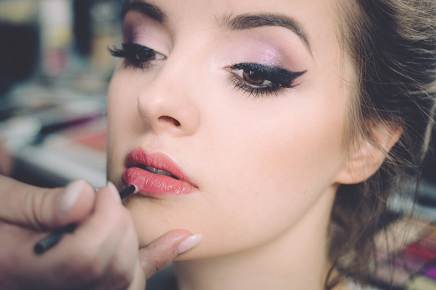 Close-up of makeup artist applying lipstick to woman's face