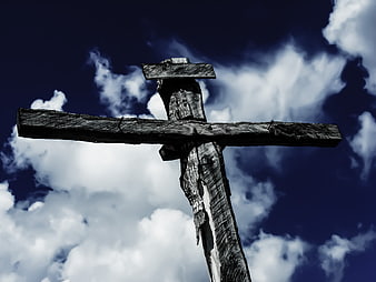 Weathered Wooden Cross Against Dramatic Blue Sky
