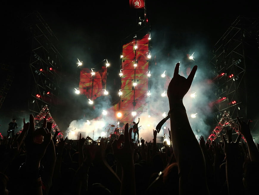Crowded rock concert audience with raised hands and stage lights