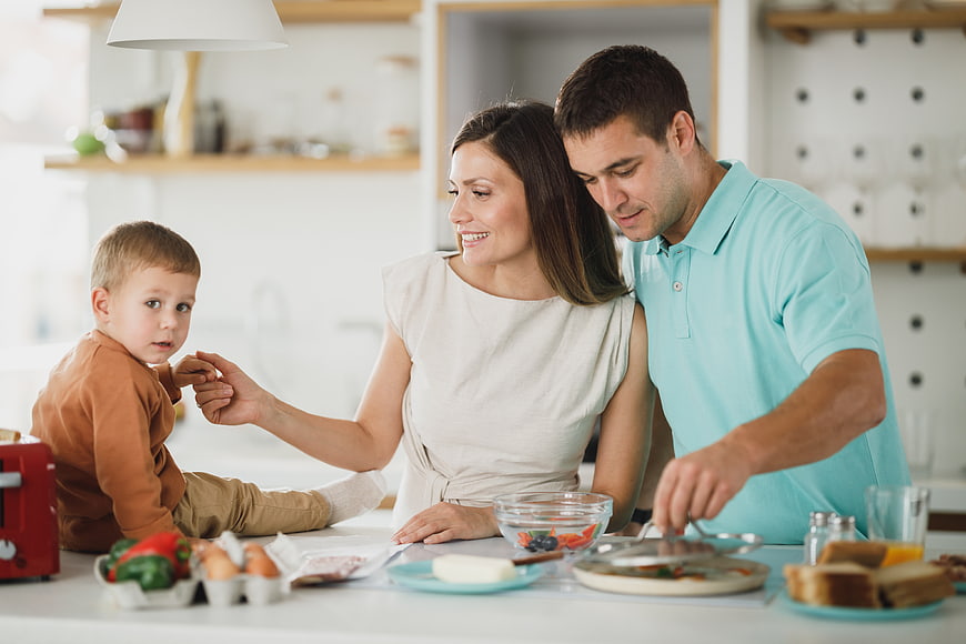 Happy family preparing breakfast together in modern kitchen