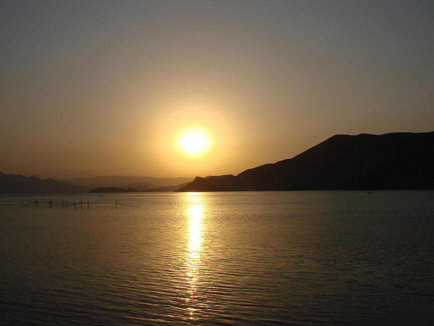 Golden sunset over calm sea with silhouetted mountains