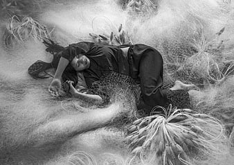 Woman sleeping in fishing net and dried grass, black and white fine art