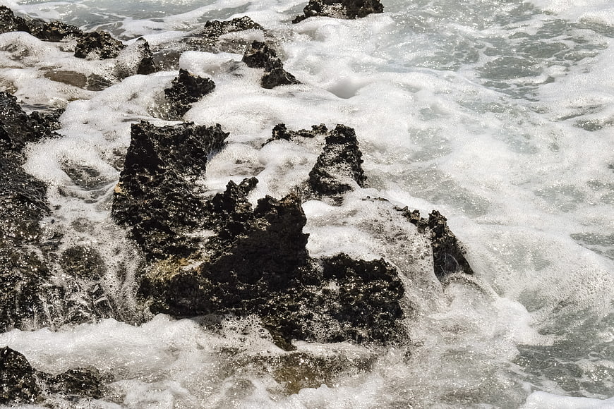 Foamy Sea Waves Crashing on Dark Rocky Shore