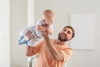 Happy Father Lifting Baby in Bright Nursery