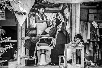 Black and white photo of men in a rustic outdoor barbershop