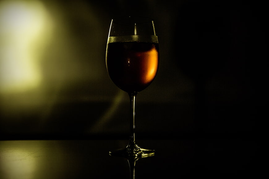 Glass of amber wine in dramatic low-key lighting