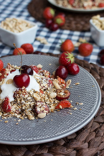 Healthy granola bowl with cherries and yogurt on gray plate