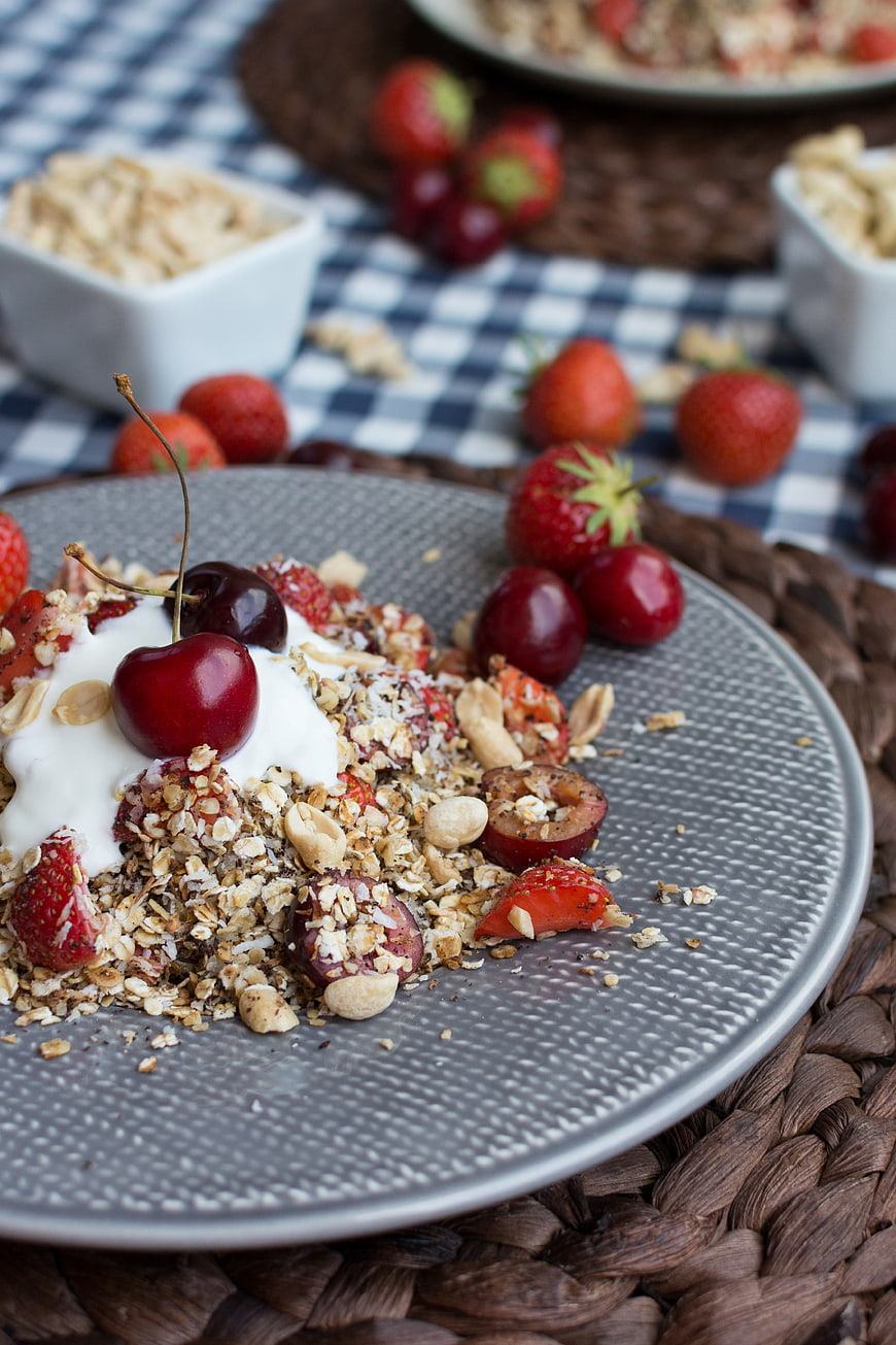 Healthy granola bowl with cherries and yogurt on gray plate