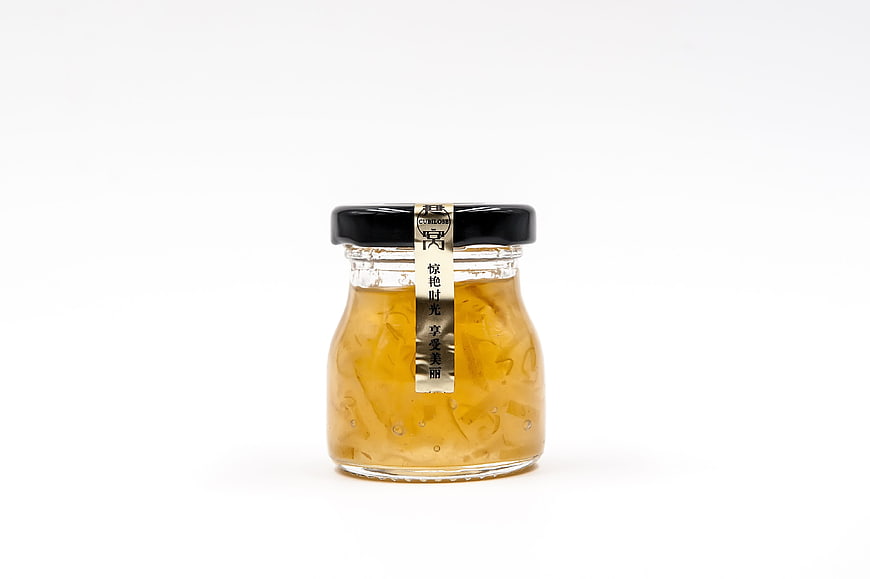 Glass jar of edible bird's nest soup with black lid on white background