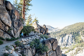 Woman hiking on rocky mountain trail with scenic forest view