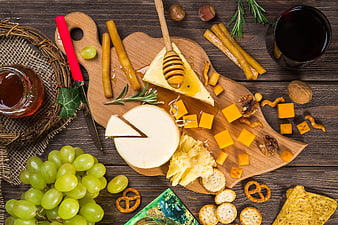 Top View Gourmet Cheese Board with Grapes, Honey, and Wine