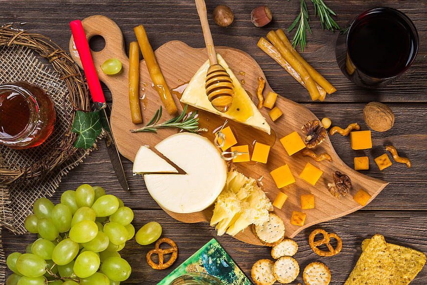 Top View Gourmet Cheese Board with Grapes, Honey, and Wine