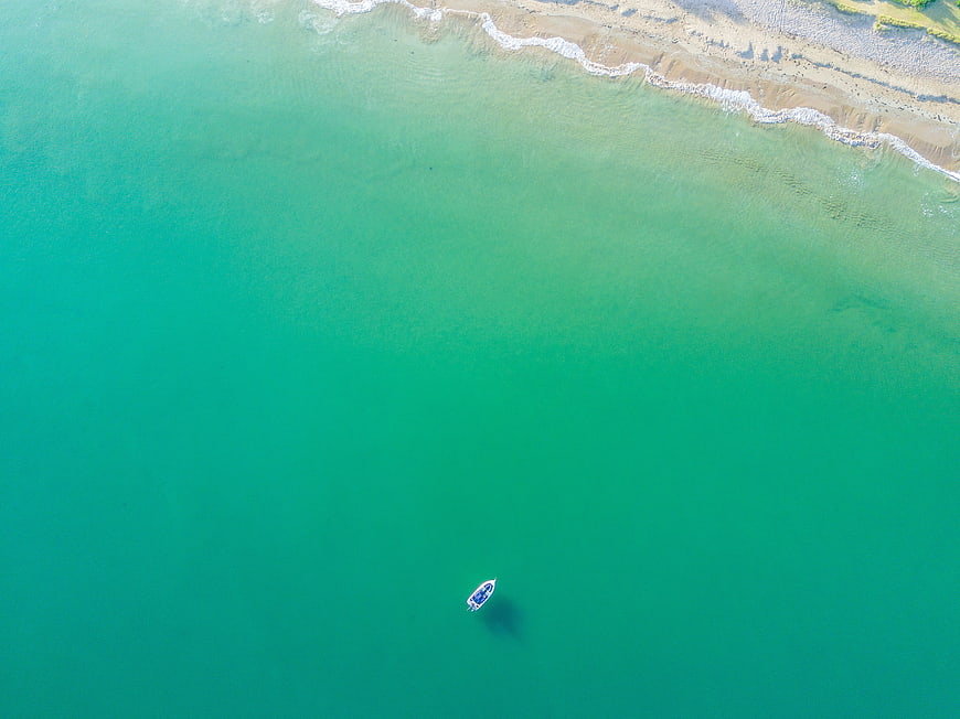 Aerial View of Turquoise Sea with Small Boat and Sandy Beach