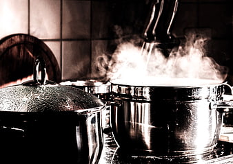 Steaming stainless steel pots on a kitchen stove
