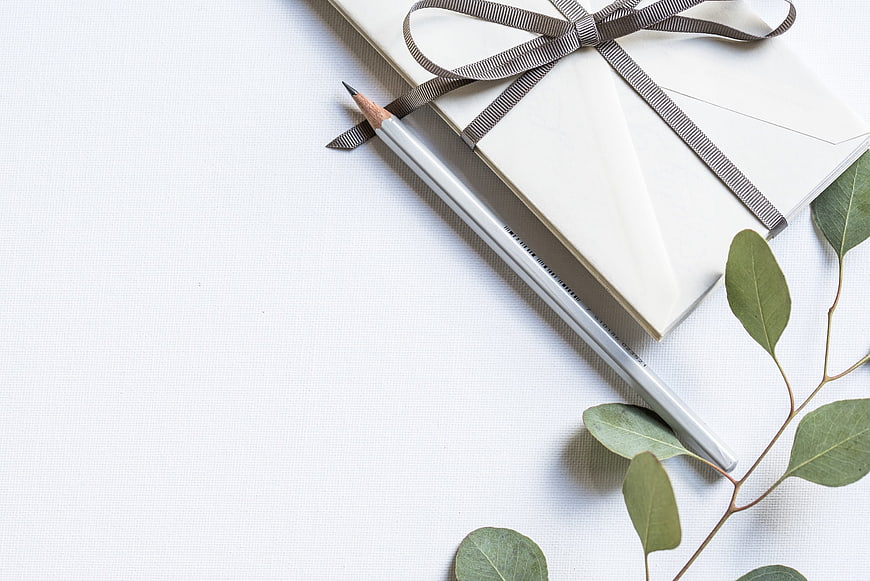 Minimalist white notebook with ribbon and eucalyptus leaves