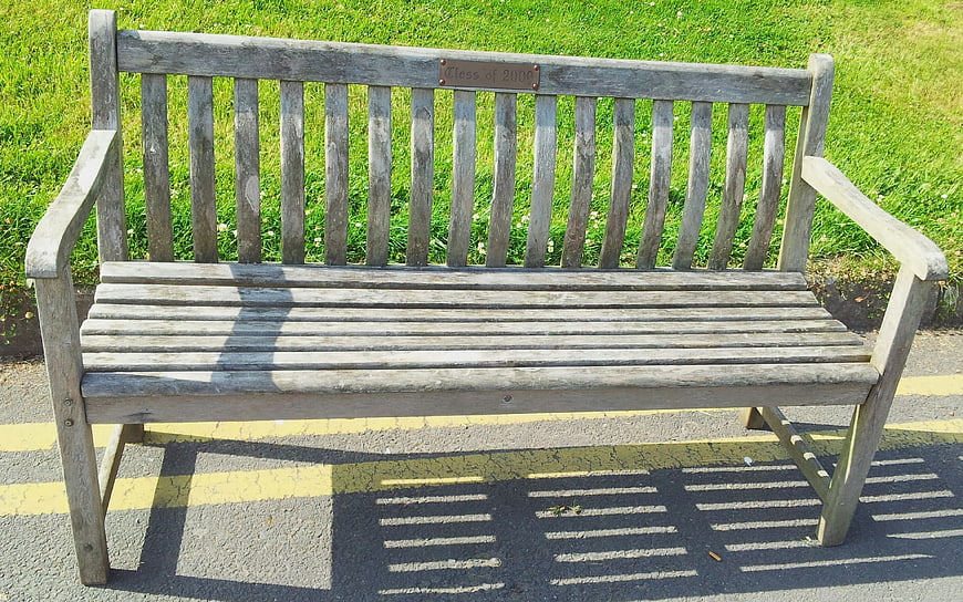 Empty wooden park bench with Class of 2000 plaque on sunny day