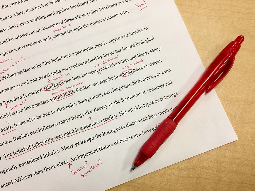 Red pen correcting essay on racism with handwritten notes