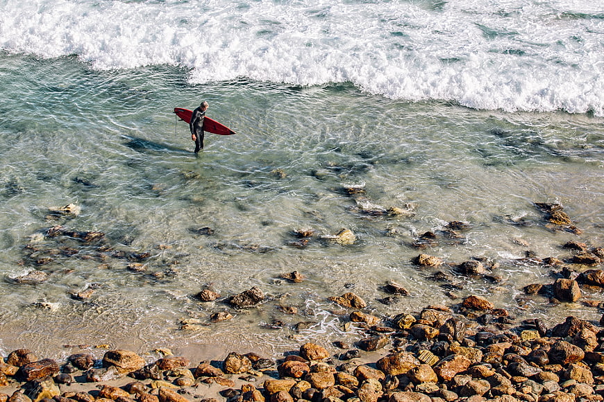 Surfer with Red Board Walking into Ocean Waves