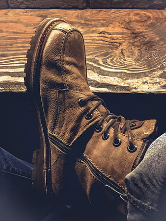 Close-up of worn brown leather work boot on wooden surface