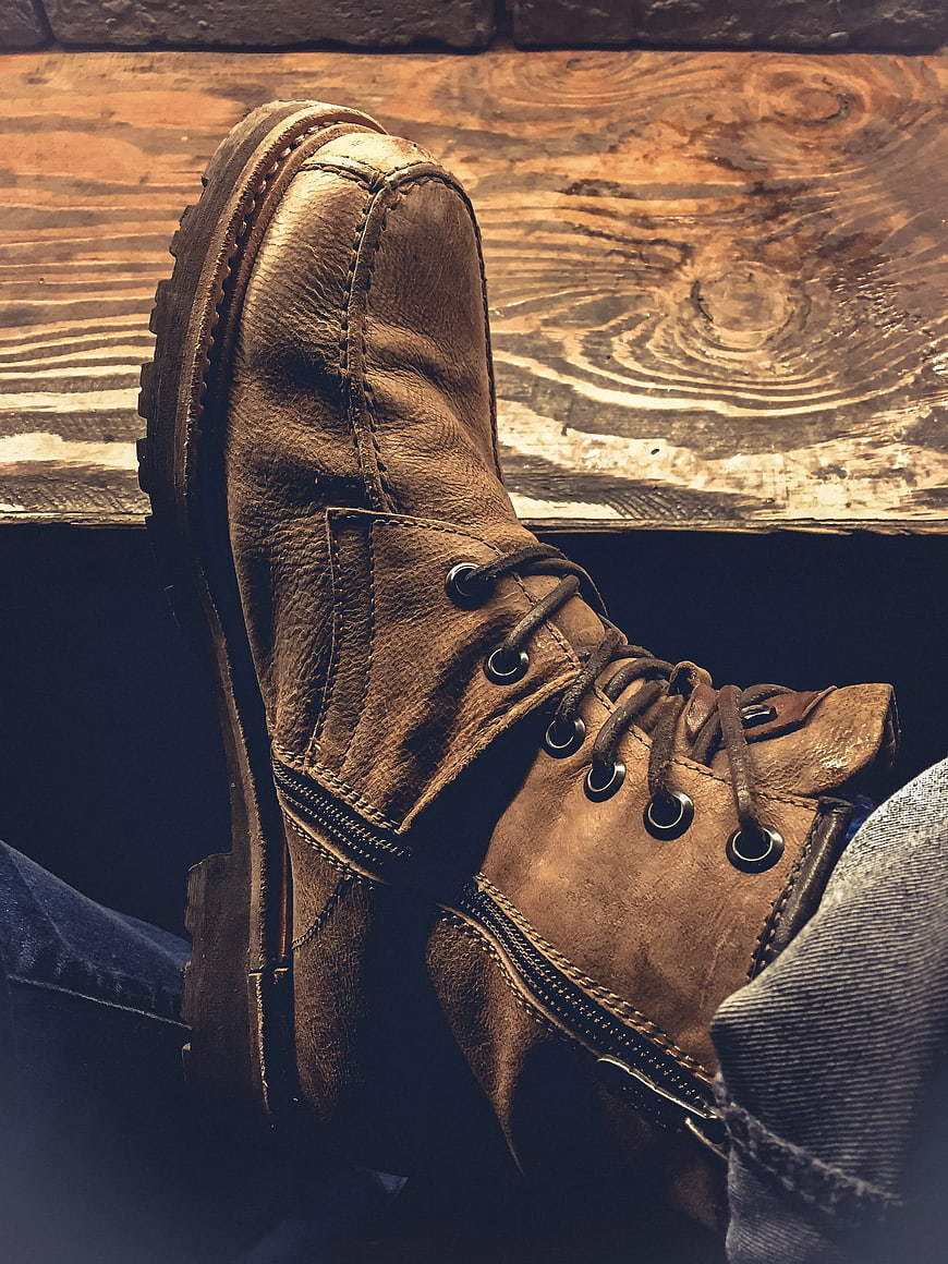 Close-up of worn brown leather work boot on wooden surface