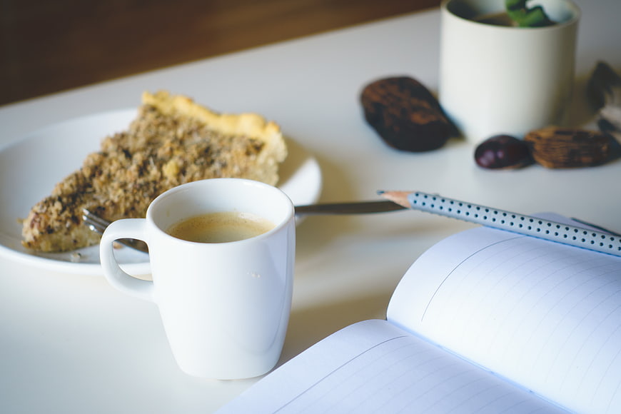 Coffee, Pie, and Notebook on White Desk