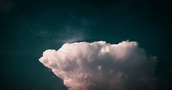 Dramatic white cumulus cloud against dark teal sky background