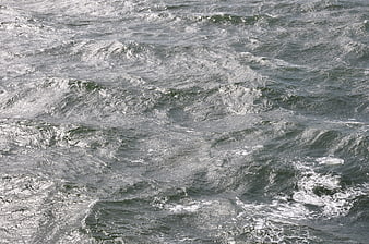 Texture of choppy gray water waves with white foam