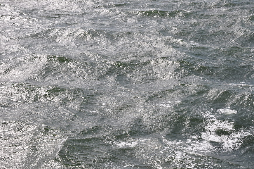 Texture of choppy gray water waves with white foam