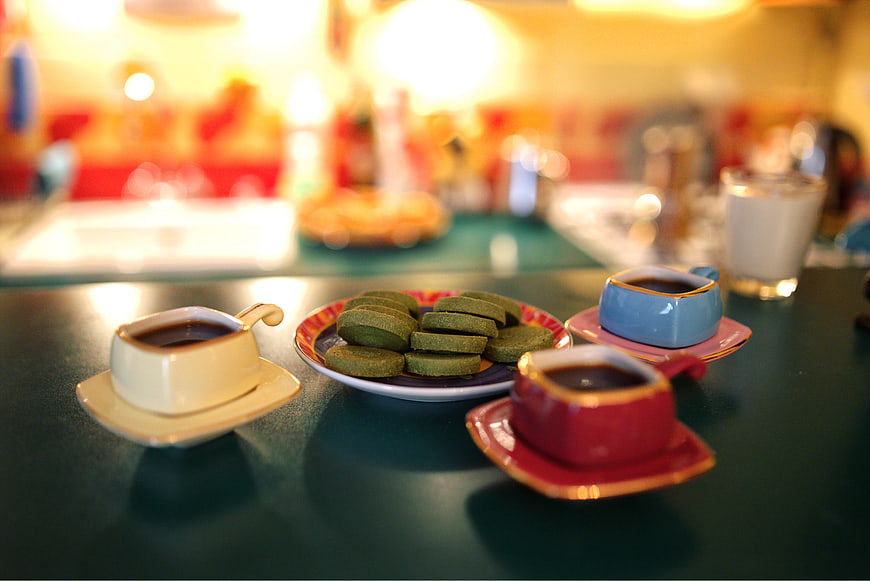 Colorful espresso cups with green tea cookies on table