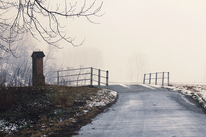 Foggy Rural Road with Metal Gate and Brick Pillar