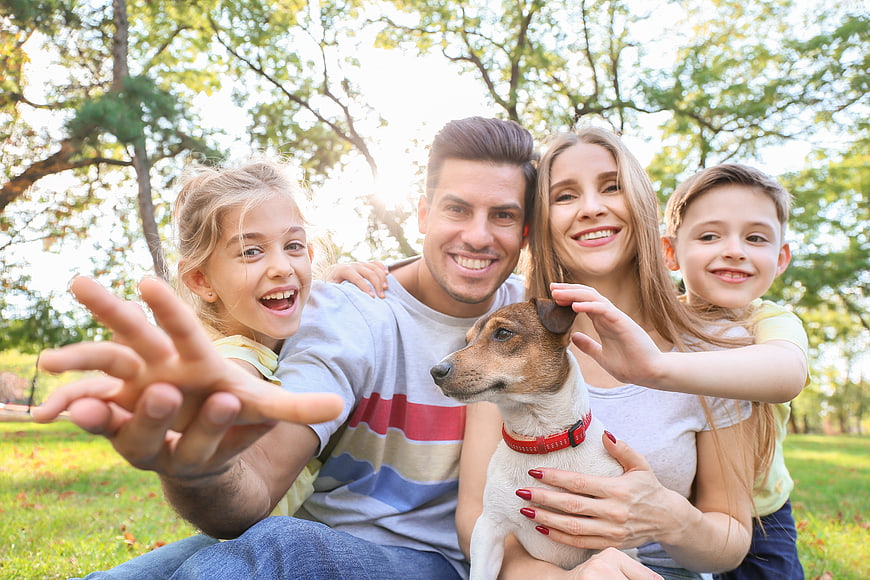 Happy family with dog taking selfie in park