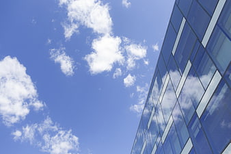 Modern Glass Building Facade Against Blue Sky with Clouds