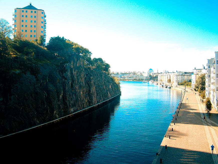 Scenic View of a River Channel with Rocky Cliff and City Promenade