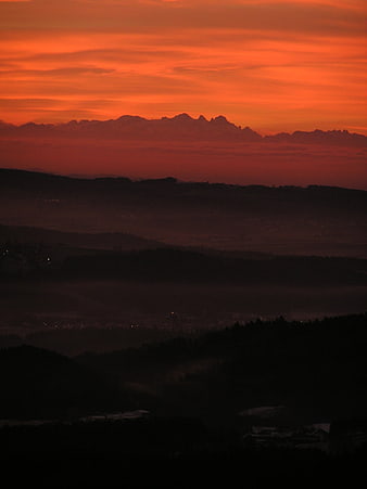 Dramatic Red Sunset Over Silhouetted Alpine Mountain Ranges