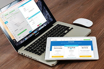 Laptop and tablet displaying business software on wooden desk