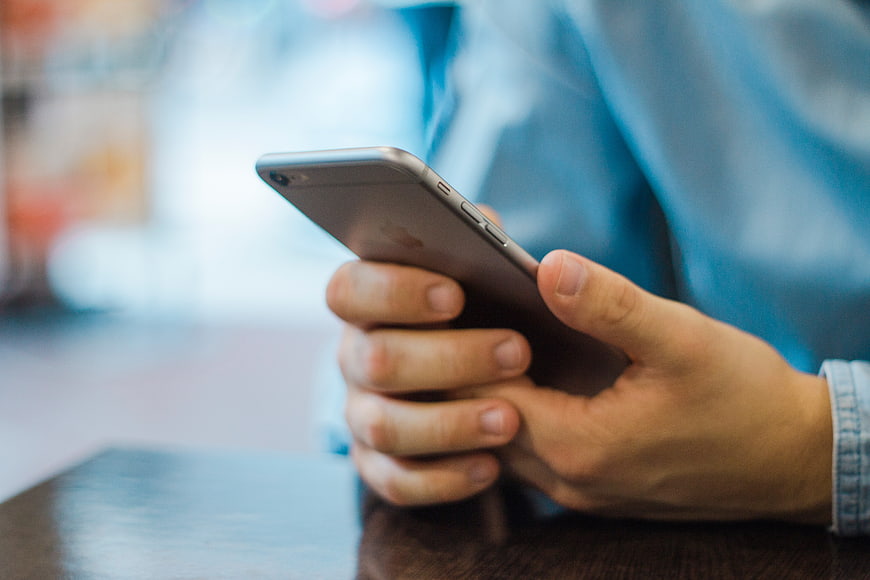 Close-up of hands holding smartphone on wooden table