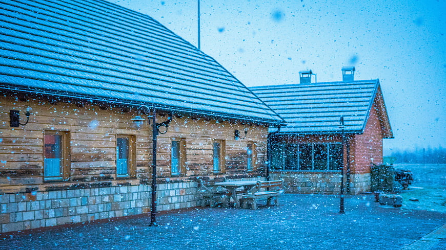 Snowy wooden cabin exterior with falling snowflakes