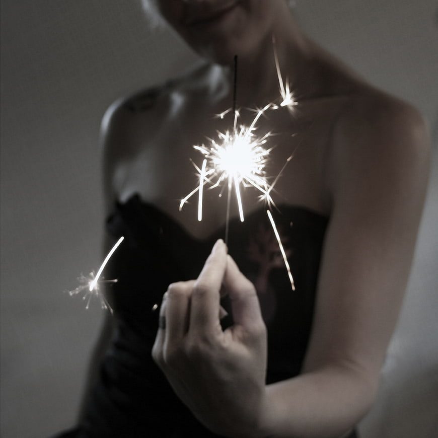 Woman Holding Sparkler in Dark Room
