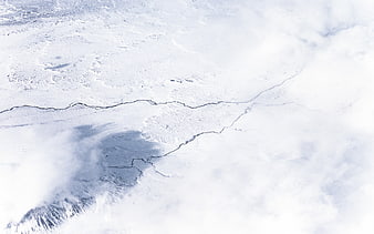 Aerial view of snow-covered landscape with winding river and clouds