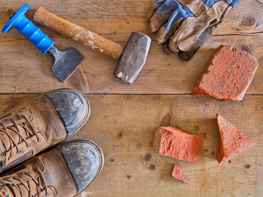 Construction tools and boots on wooden background