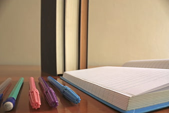 Colorful pens and open notebook on wooden desk